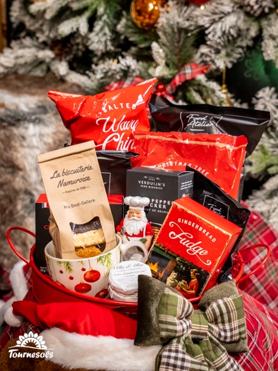 Panier garni Tournesols avec friandises, chips et chocolats devant un sapin.